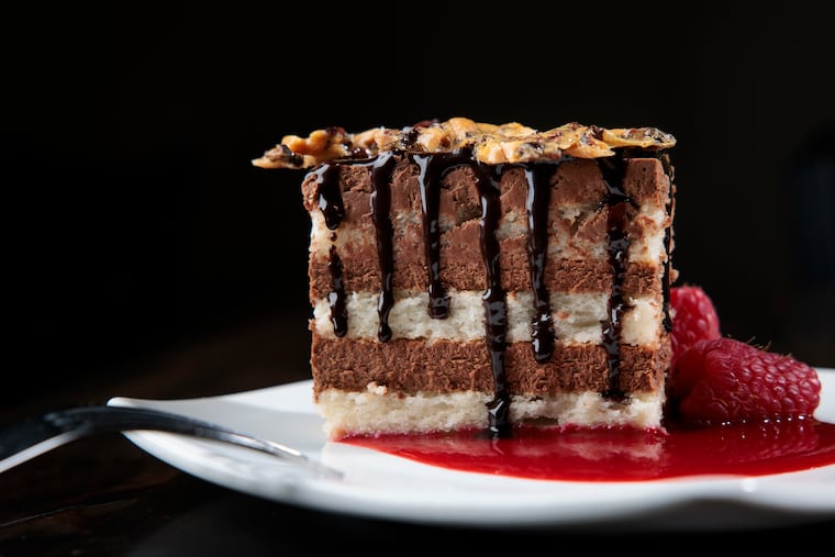 The chocolate cake at Fond in Wallingford, Delaware County. Jessie  Prawlucki Styer’s creation has shiny black drizzles of chocolate sauce dripping down the layered stripes of almond dacquoise stacked with chocolate mousse, a pool of raspberry coulis, and the sweet crackle of a cocoa nib-almond brittle crowning it all with a glorious crunch.