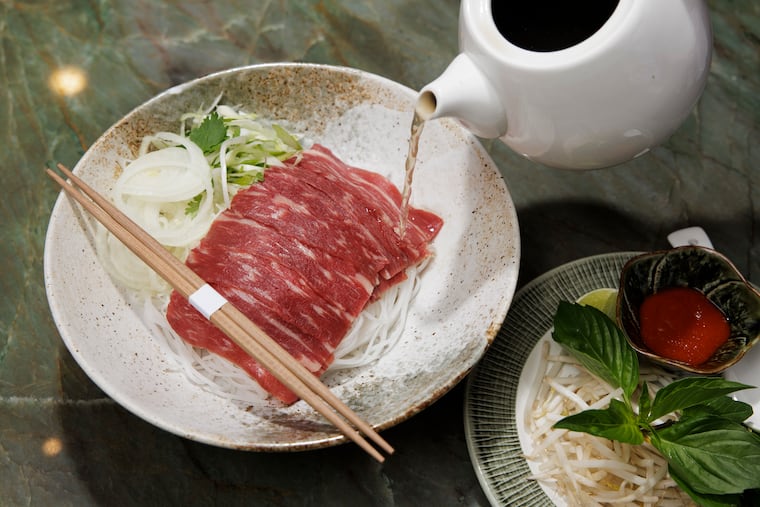 Beef broth is poured on the Wagyu beef pho at Maison Lotus in Wayne, Pa.