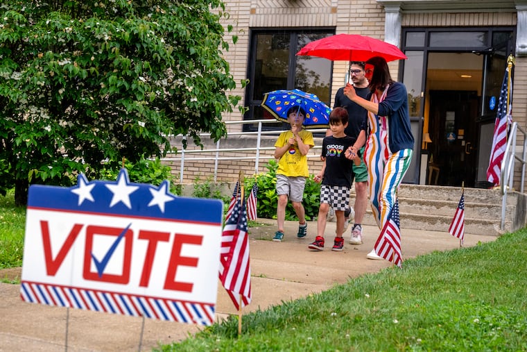 Stopping on their way to dropping their sons off at school, Emily Getzinger and Matt Zmijewski leave their polling place with Booker, 9, and Winslow, 6, after casting their ballots inside McDaid Hall at St. Teresa of Calcutta Parish Holy Saviour Church in Westmont.
