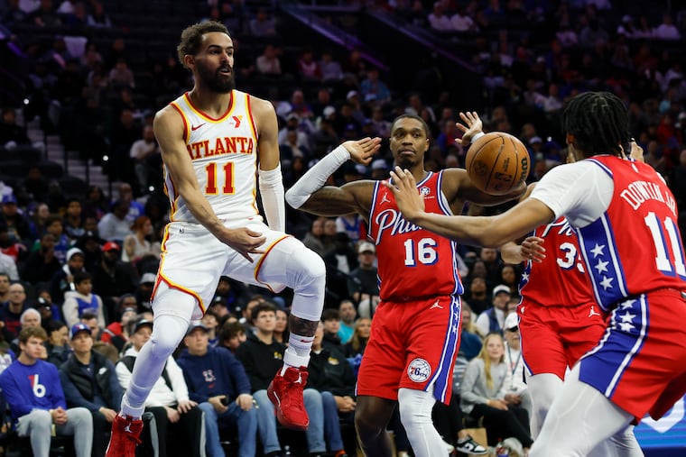 Hawks guard Trae Young passes the basketball past Sixers guard’s Lonnie Walker IV and Jeff Dowtin Jr., in the fourth quarter.