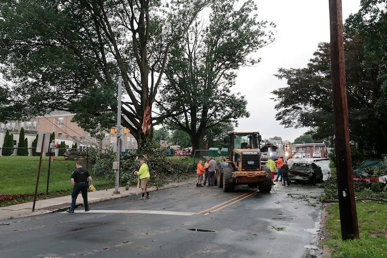 Upper Darby officials arrive at the scene on Burmont Road where part of a tree from the front of Garrettford Elementary School came crashing down on a car that was driving by during the storm that rolled through the area on Thursday. Poles and wires were also brought down, causing a large power outage in the area.