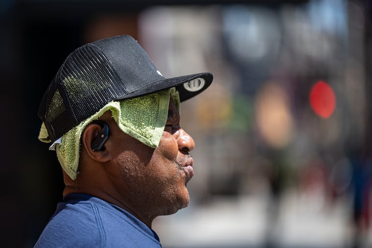 Dwayne Chapman wears a wet cloth on his head to combat the heat while crossing Broad Street on Wednesday. Things are about to get better.