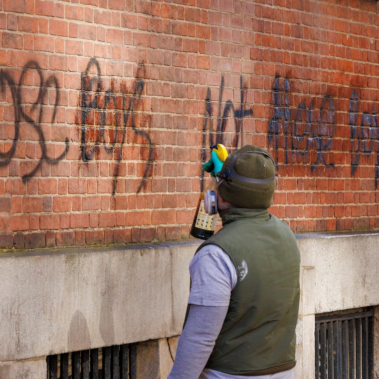 A National Parks Service worker sprays graffiti for removal on side of Congress Hall, Philadelphia Independence Hall, on Jan. 17. It reads, “Those Boys Not these Boys.”