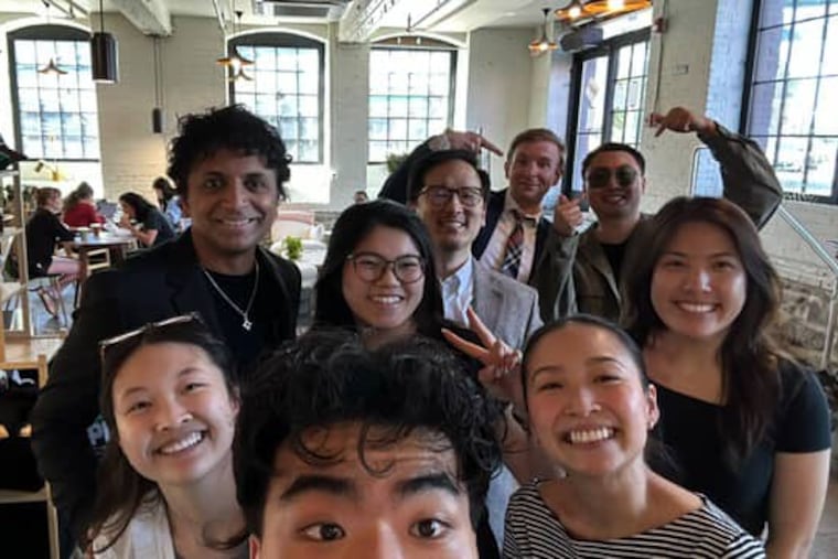 M. Night Shyamalan stops by Càphê Roasters in Kensington. He poses for a picture with the cafe staff.